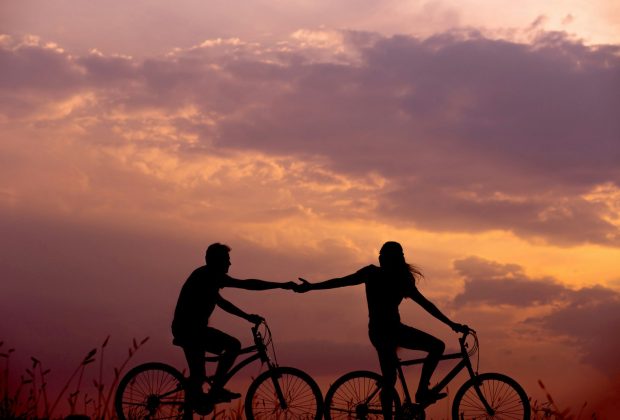 woman on bike reaching for man's hand behind her also on bike