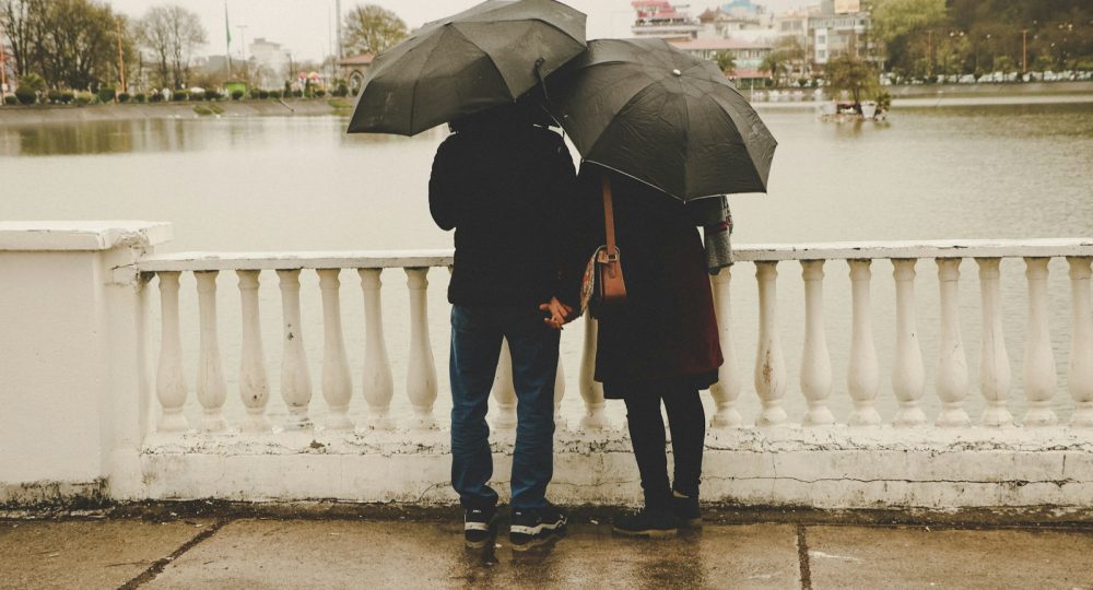 man and woman holding black umbrellas