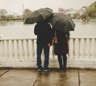 man and woman holding black umbrellas